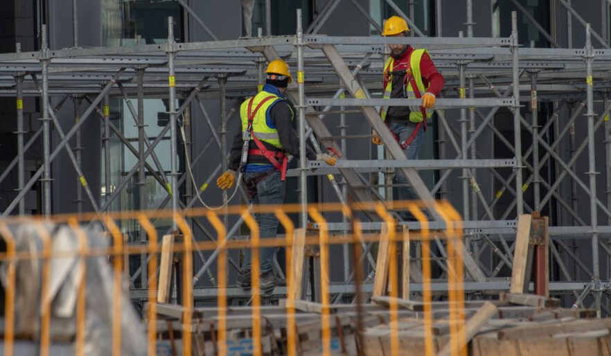 Two workers wearing safety equipment on an active construction site